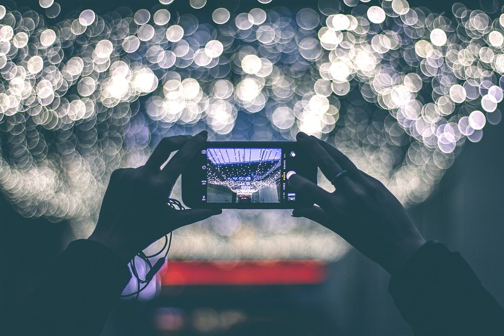 Hands holding a phone, filming a show full of lights