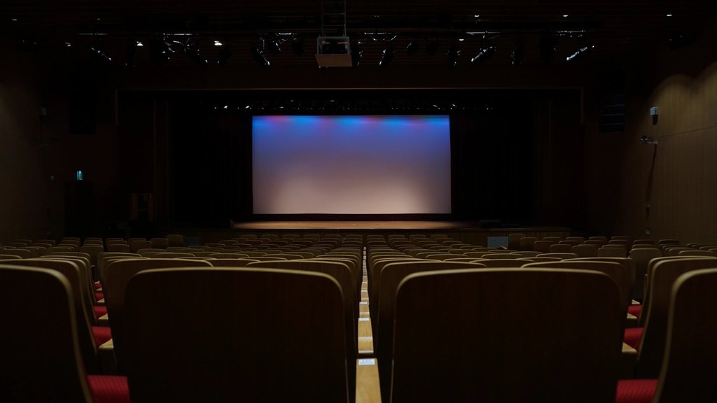 A dark auditorium facing a glowing cinema screen